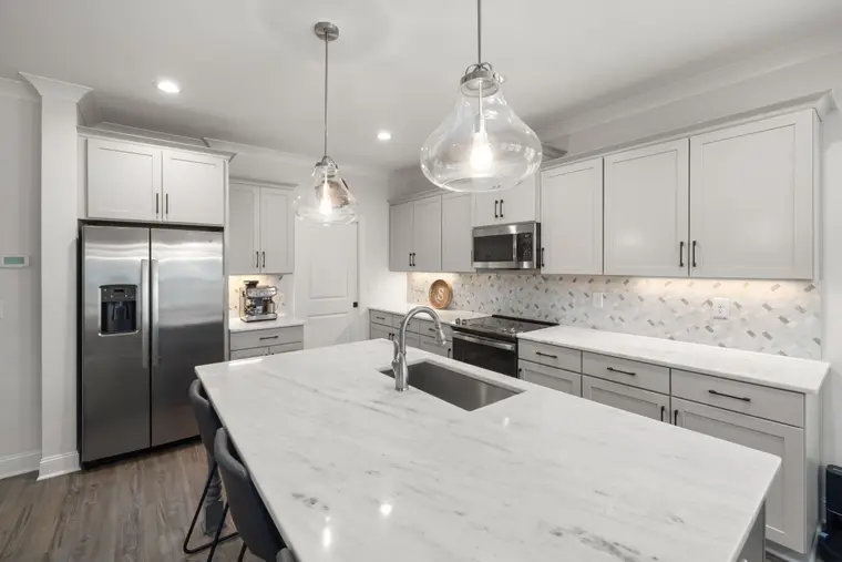 Kitchen island topped in veined stone with seating along one side